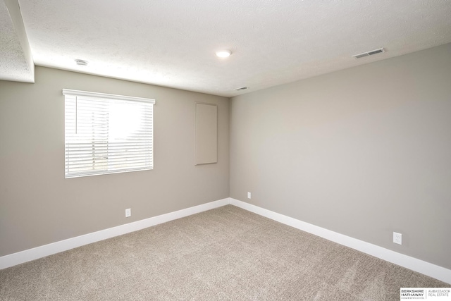 carpeted empty room featuring a textured ceiling, visible vents, and baseboards