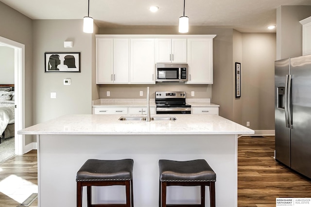 kitchen with dark wood-style flooring, baseboards, recessed lighting, a breakfast bar, and appliances with stainless steel finishes