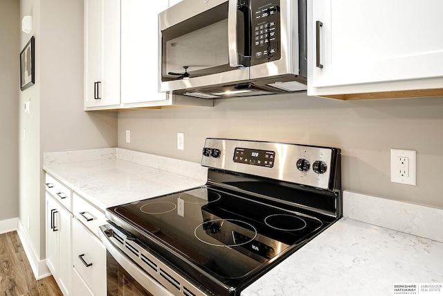 kitchen with stainless steel appliances, a ceiling fan, white cabinetry, and light stone counters