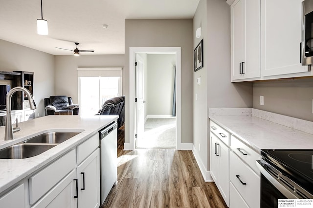 kitchen featuring stainless steel appliances, a ceiling fan, a sink, light wood-style floors, and open floor plan