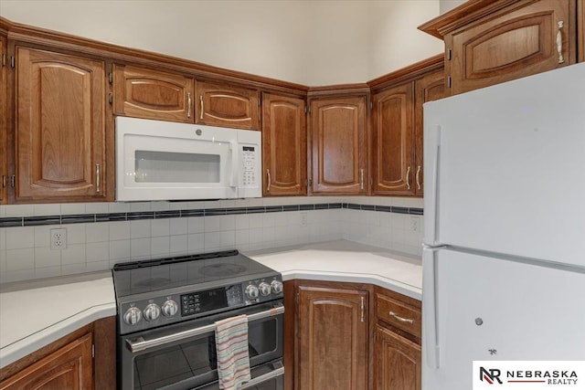 kitchen featuring backsplash, light countertops, and white appliances