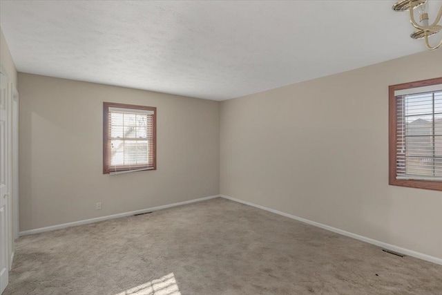 carpeted empty room with visible vents, baseboards, and a healthy amount of sunlight