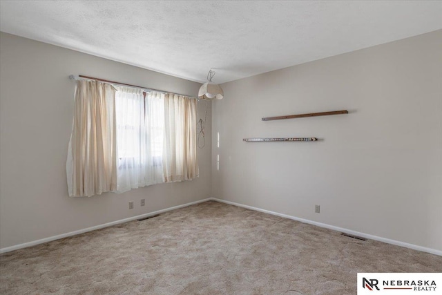 empty room featuring carpet floors, visible vents, and baseboards