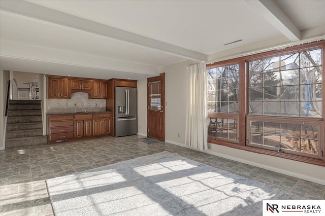 kitchen featuring visible vents, beam ceiling, baseboards, decorative backsplash, and stainless steel refrigerator with ice dispenser