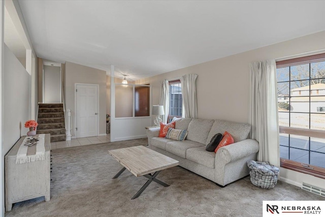 living area featuring lofted ceiling, stairs, visible vents, and plenty of natural light