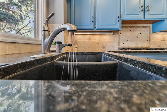 details featuring blue cabinets, backsplash, and dark stone counters