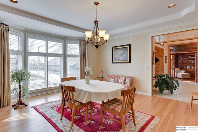 dining space featuring a chandelier, a raised ceiling, crown molding, recessed lighting, and light wood-type flooring