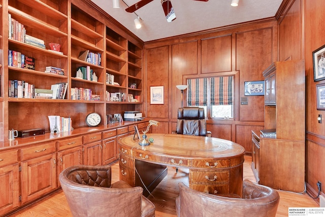 office featuring light wood finished floors, ceiling fan, built in shelves, and wooden walls