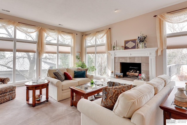 living area with plenty of natural light, a fireplace, and light carpet