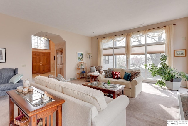 living area with light colored carpet and arched walkways