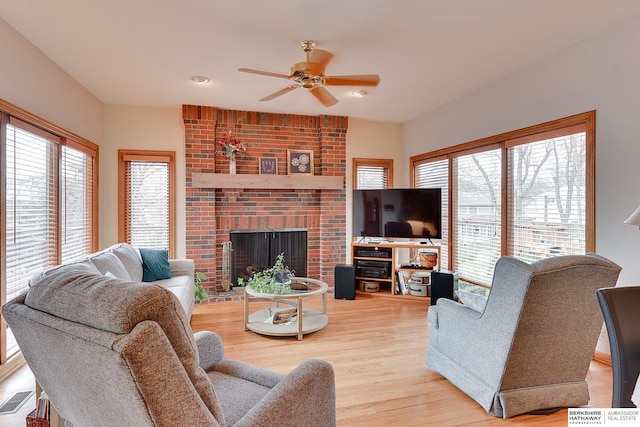 living area featuring plenty of natural light, ceiling fan, wood finished floors, and a fireplace