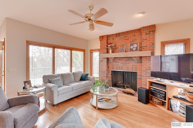 living area featuring ceiling fan, wood finished floors, and a fireplace