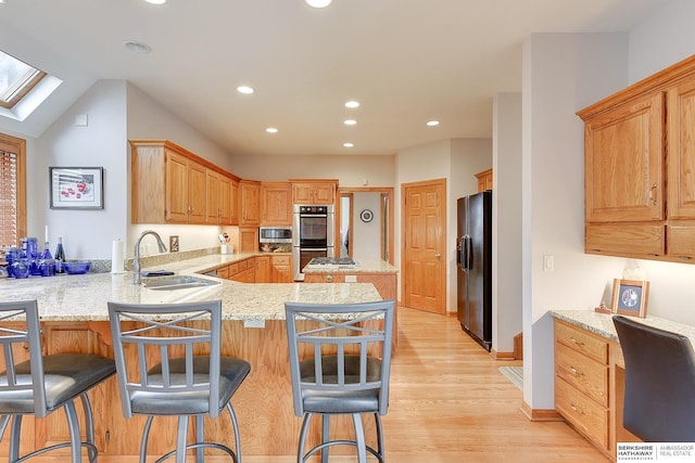 kitchen with a sink, a skylight, stainless steel appliances, a peninsula, and recessed lighting