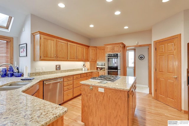 kitchen with stainless steel appliances, a sink, a skylight, a center island, and recessed lighting