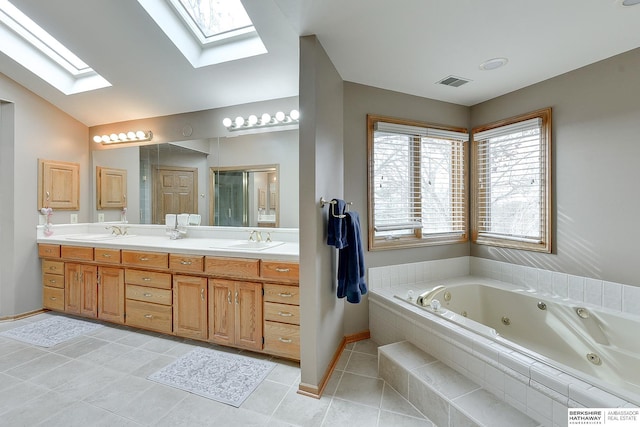 full bathroom featuring a skylight, a tub with jets, double vanity, tile patterned floors, and baseboards