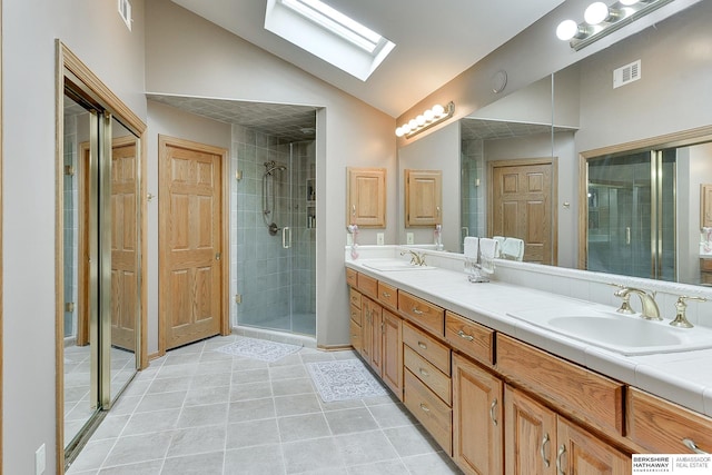 bathroom with lofted ceiling, a skylight, a stall shower, double vanity, and tile patterned floors