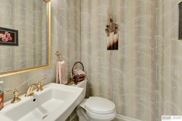 bathroom featuring a sink, toilet, and curtained shower