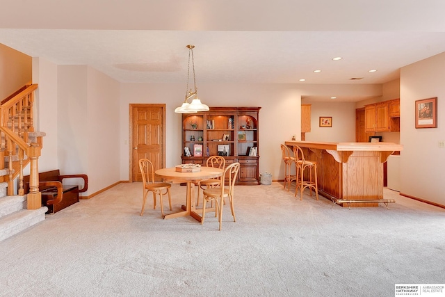 dining space with a bar, stairs, light carpet, baseboards, and recessed lighting