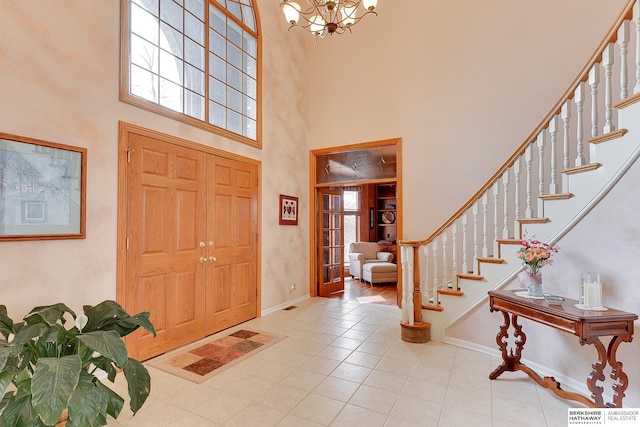 tiled foyer with a high ceiling, stairway, plenty of natural light, and a chandelier