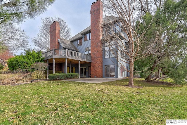 back of property featuring a wooden deck, a lawn, a patio, and a chimney