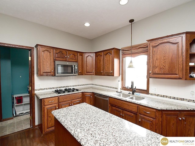 kitchen featuring tasteful backsplash, a sink, brown cabinetry, stainless steel appliances, and dark wood finished floors