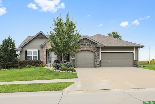 view of front of home with concrete driveway, stone siding, an attached garage, a front yard, and roof with shingles
