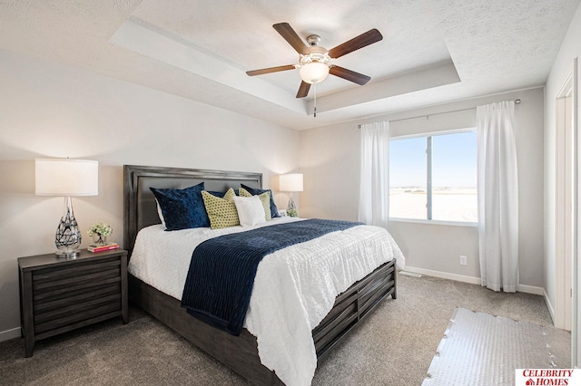 carpeted bedroom featuring a textured ceiling, baseboards, a raised ceiling, and a ceiling fan