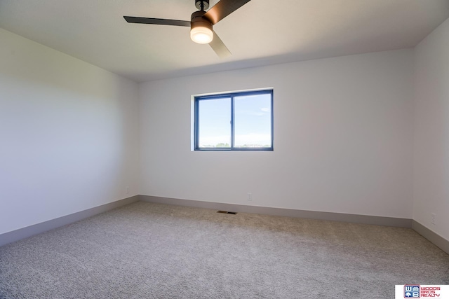 unfurnished room featuring baseboards, visible vents, light colored carpet, and ceiling fan