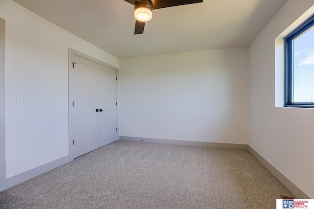 unfurnished bedroom featuring light colored carpet, a ceiling fan, and multiple windows