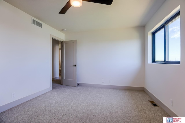 unfurnished room featuring visible vents, a ceiling fan, and light colored carpet