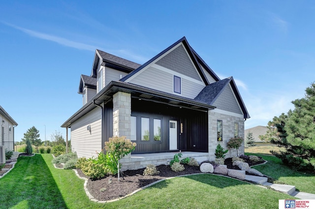 back of property with stone siding, a lawn, and roof with shingles