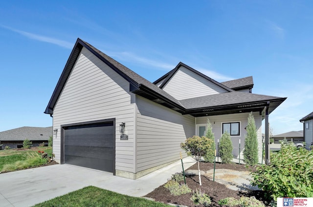 view of front of home with an attached garage, roof with shingles, and driveway