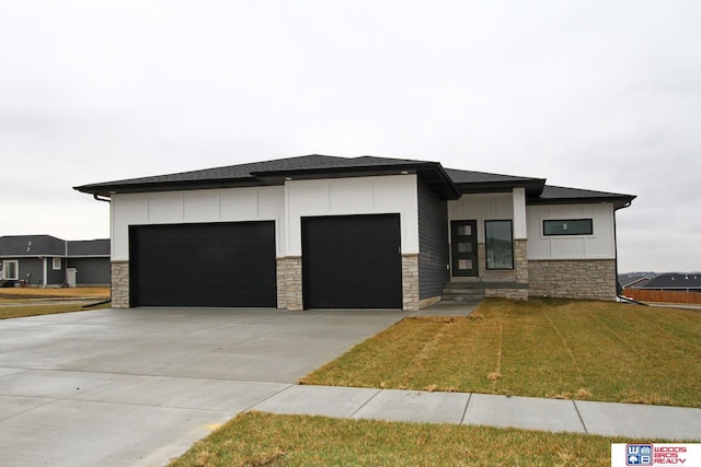 prairie-style house featuring a garage, stone siding, and concrete driveway