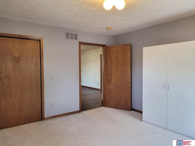 1321 Frances St, Goehner, NE 68364 - unfurnished bedroom featuring a textured ceiling, baseboards, visible vents, light colored carpet, and a closet