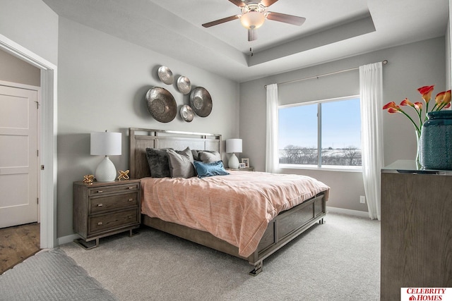 bedroom featuring a ceiling fan, baseboards, a raised ceiling, and light colored carpet