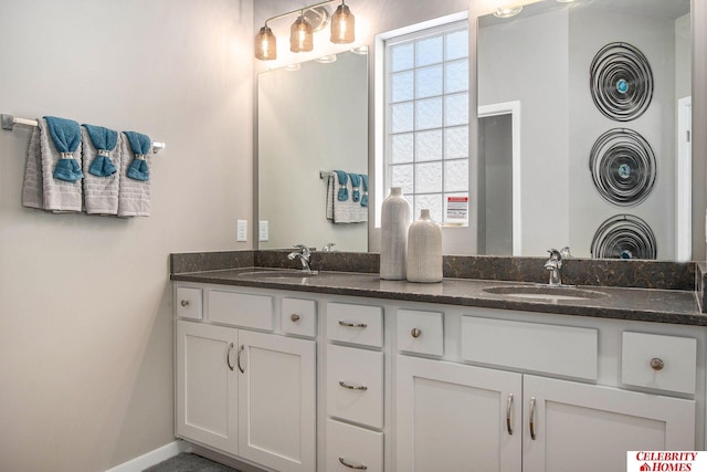 full bath featuring double vanity, baseboards, and a sink