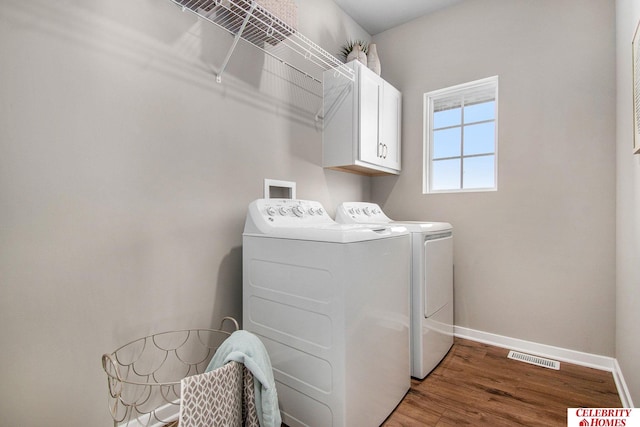 washroom featuring wood finished floors, visible vents, washing machine and clothes dryer, baseboards, and cabinet space