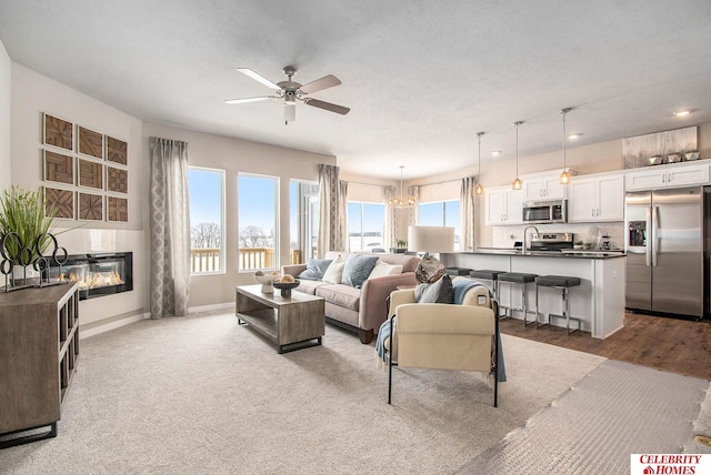 living room featuring baseboards, a ceiling fan, and a glass covered fireplace