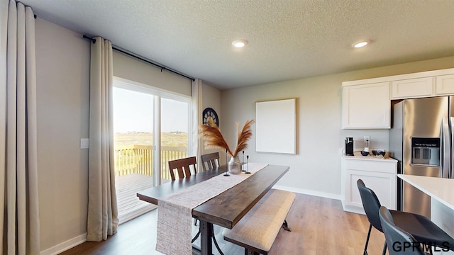 dining space featuring recessed lighting, light wood-type flooring, a textured ceiling, and baseboards