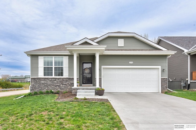 view of front of house with a front lawn, driveway, stone siding, a shingled roof, and a garage