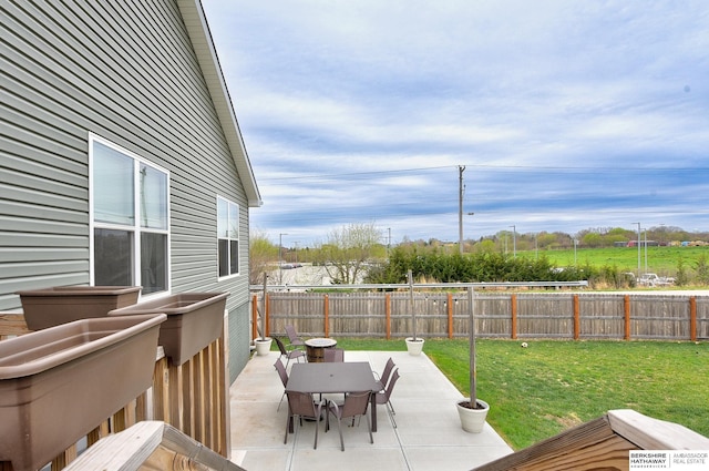 wooden terrace featuring a fenced backyard, outdoor dining space, a patio, and a lawn
