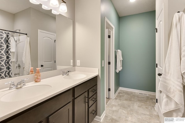 bathroom featuring double vanity, visible vents, baseboards, and a sink