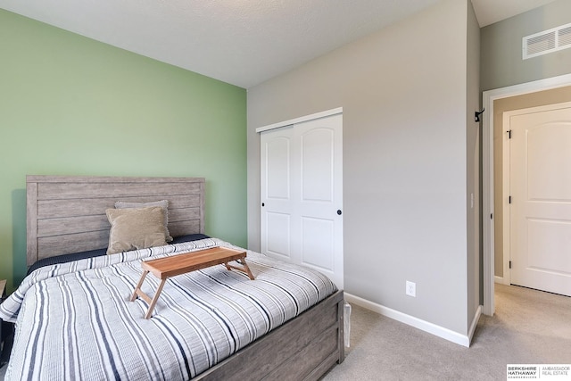 bedroom featuring a closet, visible vents, baseboards, and light colored carpet