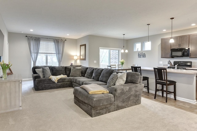 living area featuring light carpet, baseboards, and recessed lighting