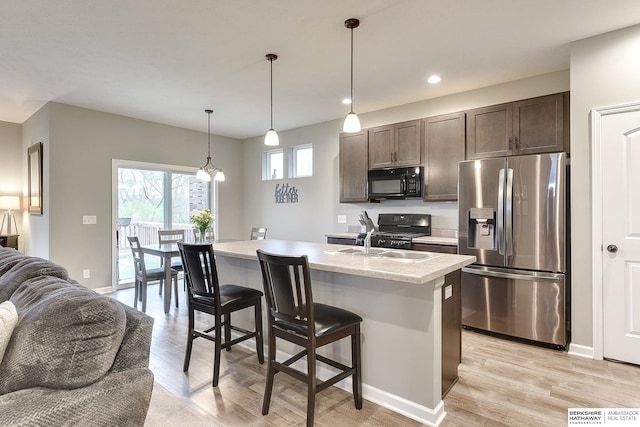 kitchen with dark brown cabinets, stainless steel refrigerator with ice dispenser, open floor plan, and black microwave