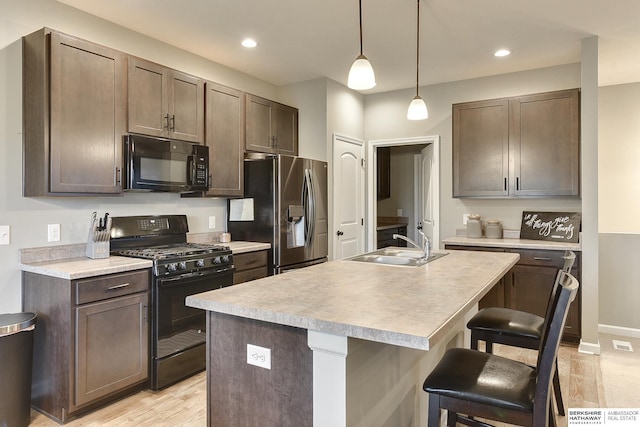 kitchen with black appliances, a kitchen breakfast bar, a sink, and light countertops