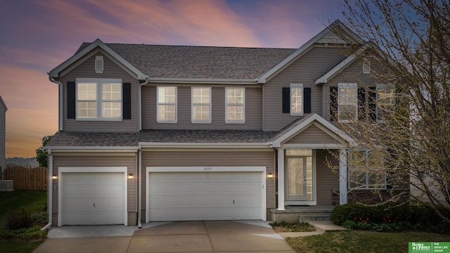 view of front of property featuring an attached garage, driveway, and roof with shingles