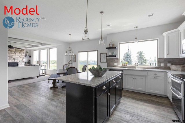 kitchen featuring tasteful backsplash, open floor plan, dark cabinetry, range with two ovens, and a kitchen island