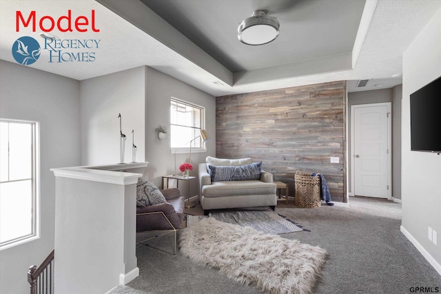 sitting room featuring an upstairs landing, baseboards, wood walls, carpet flooring, and visible vents