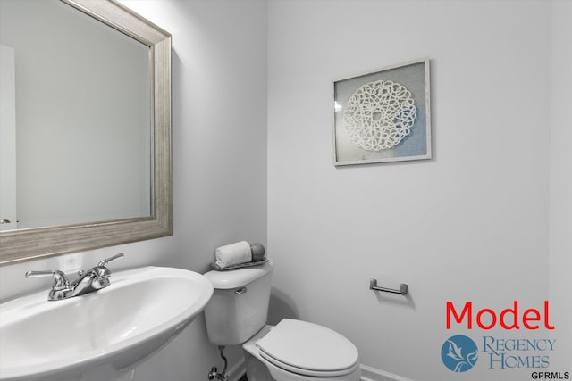 bathroom with baseboards, a sink, and toilet